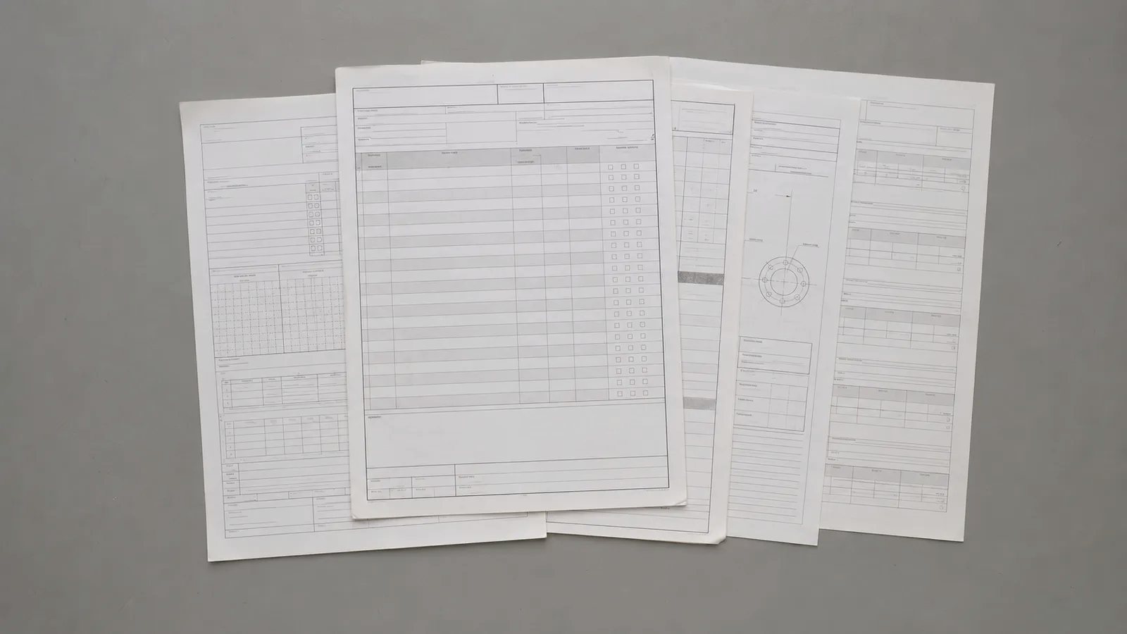 書式の異なる複数の報告書が並べられ、記入の粒度がそろっていない様子